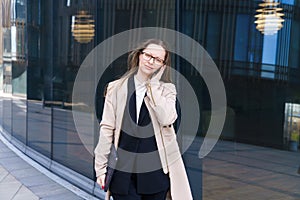 Business woman glasses with laptop her hands talking phone near business center