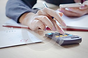 Business woman hand calculating her monthly expenses during tax season.