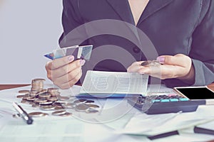 business woman hand calculating her monthly expenses during tax season with coins, calculator, credit card and account bank