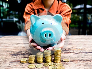 Business woman hand carry blue piggy bank with gold coins pile growth graph, Saving money for future investment plan and