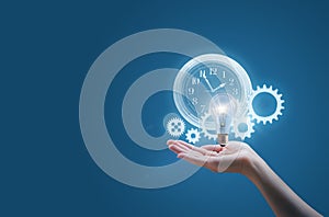 Business woman in the hand of a clock gears and the lamp symbolizes the effective implementation of business ideas photo