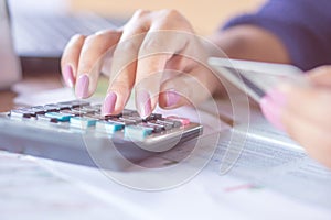 Business woman hand counting on calculator using her credit card for shopping online