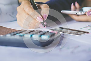 Business woman hand counting monthly expenses on calculator with blur background of credit card and smart phone