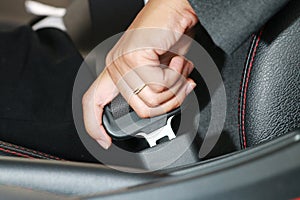 Business woman hand fastening a seat belt.