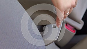 Business woman hand fastening a seat belt in the car.