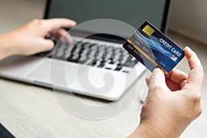 Business woman hand hold credit card to shopping internet online bill on computer, Debit saving purchase buy on table background.