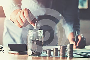 business woman hand holding coins puting into glass. concept saving money finance and accounting