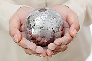 Business woman hand holding jigsaw puzzle globe