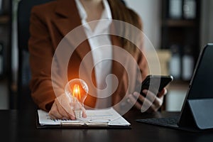 Business woman hand holding light bulb, concept of new ideas with innovation and creativity, at home office in the morning