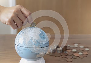 Business woman hand putting one pound coin in to glob bank for donate money helping the earth, People saving money for the future