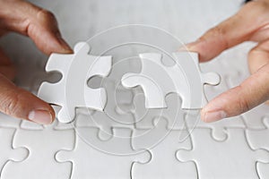 Business woman hand is trying to connect couple White jigsaw puzzle piece on a blue background. Symbol of association and