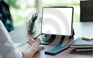 Business woman hand working at a computer and writing on a noteped with a pen in the office