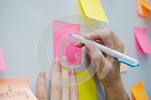 Business woman hand writing with colored sheets sticky note paper on white board background