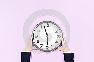 Business woman hands hold wall clock on pastel blue background