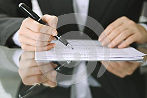Business woman hands with pen over document of contract at glass table. Agreement signing concept
