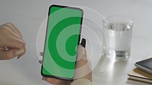 Business Woman hands type on green chroma key smartphone at white table with gadgets in office slow motion close view. A