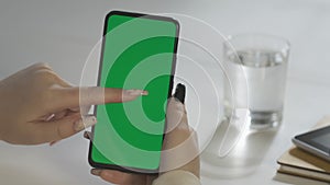 Business Woman hands type on green chroma key smartphone at white table with gadgets in office slow motion close view. A