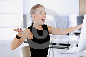 Business woman happy and excited while working with computer in modern office. Secretary or female lawyer looks