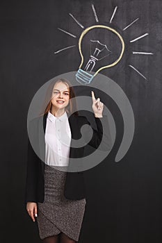 A business woman has a great idea and raises her finger up pointing to a lightbulb on the board.