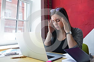 Business woman having headache during work on laptop computer