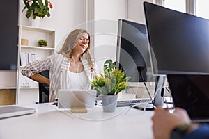 Business woman having pain in the back while sitting at her desk