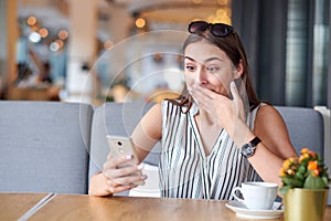 Business woman having surprised expression after recieving message in coffee shop. Wow effect