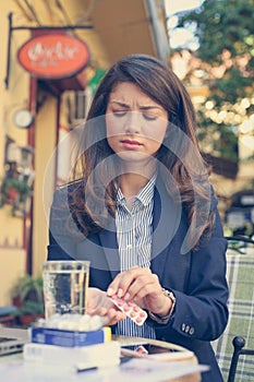 Business woman with head pains using tablets .