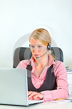 Business woman with headset working on laptop