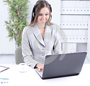 Business woman with headset working on laptop.