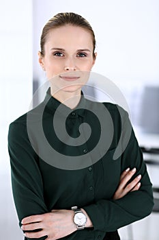 Business woman headshot in modern office. Secretary or female lawyer standing straight and looking at camera. Business