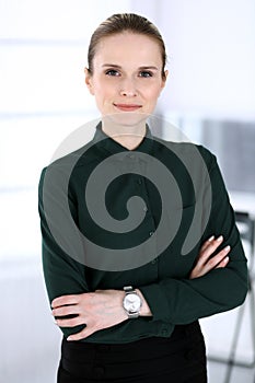 Business woman headshot in modern office. Secretary or female lawyer standing straight and looking at camera. Business