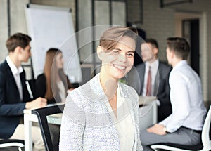 Business woman with her staff, people group in background at modern bright office indoors.