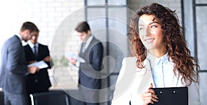 Business woman with her staff, people group in background at modern bright office indoors.