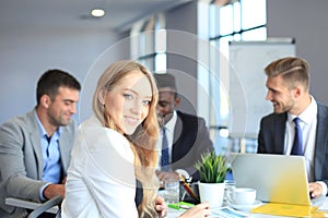 Business woman with her staff, people group in background at modern bright office indoors.