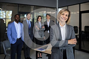 Business woman with her staff, people group in background at modern bright office indoors.