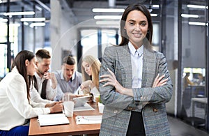 Business woman with her staff, people group in background at modern bright office indoors.