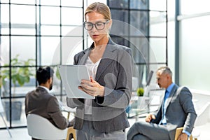 Business woman with her staff, people group in background at modern bright office indoors.