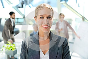 Business woman with her staff, people group in background at modern bright office indoors.