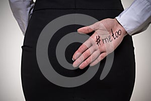 Business woman hiding behind her back a palm with an inscription me too. Stop sexual harassment against women. metoo concept