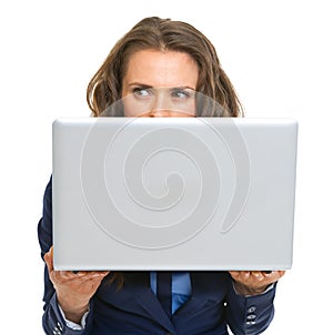 Business woman hiding behind laptop