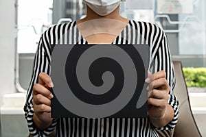 Business woman holding blank chalk board sign wearing face mask after lockdown