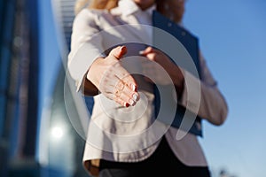 Business woman holding blue folder giving arm extended for handshake