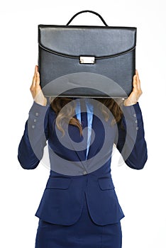 Business woman holding briefcase in front of face