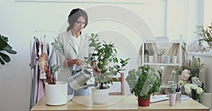 Business woman holding can watering green plants in office