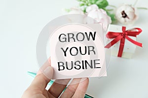business woman holding a card with text GROW YOUR BUSINESS, business concept image with soft focus background