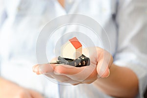 Business woman holding a cipher lock under a miniature house, symbolizing the concept of home security or insurance