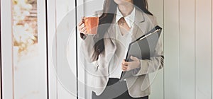 Business woman holding coffee cup and portfolio in office