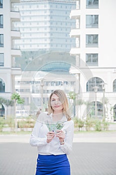 Business woman holding euro banknotes on city buildings background