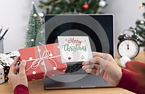 Business woman holding giftbox and greeting card on office table in Christmas day