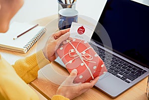 Business woman holding giftbox and greeting card on office table in Christmas day